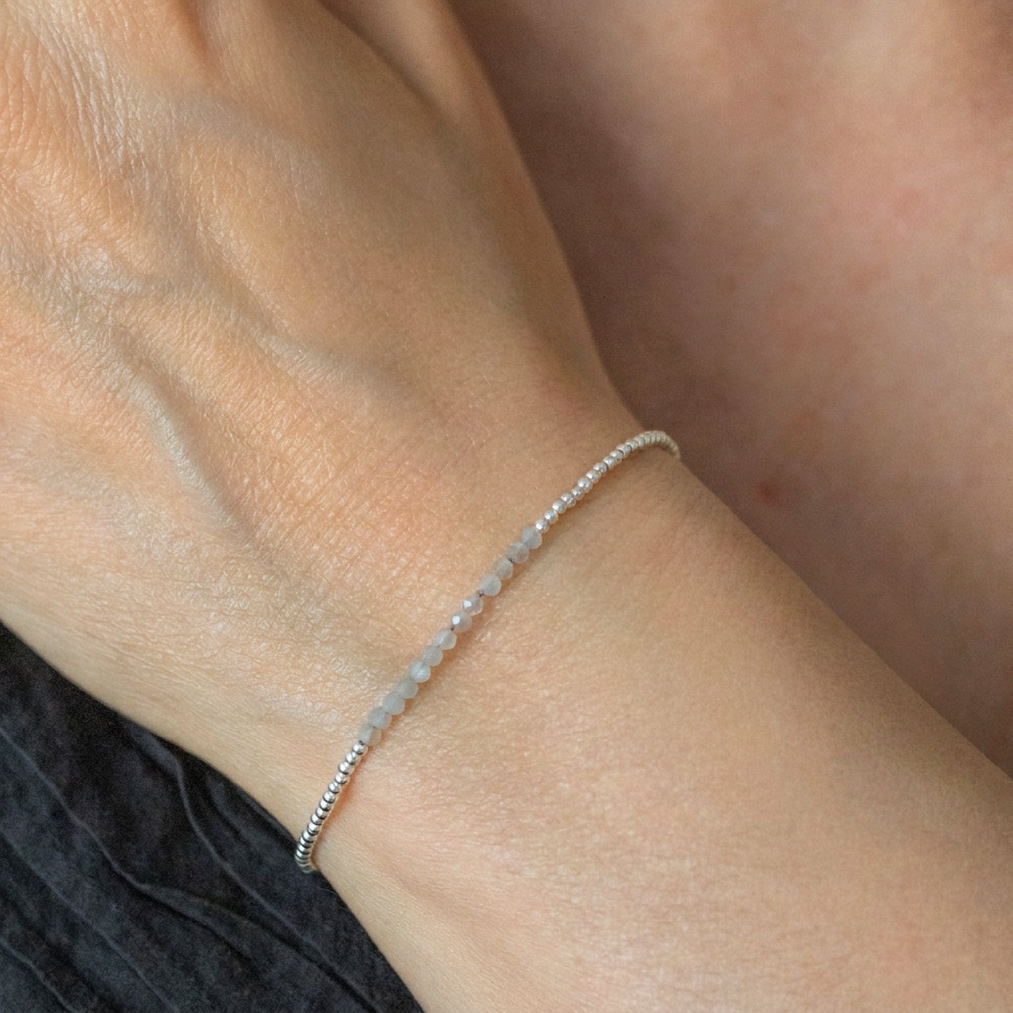 Am Handgelenk des Models hängt ein ultra dünnes Silberarmband mit grauen Mondstein-Perlen in der Mitte.