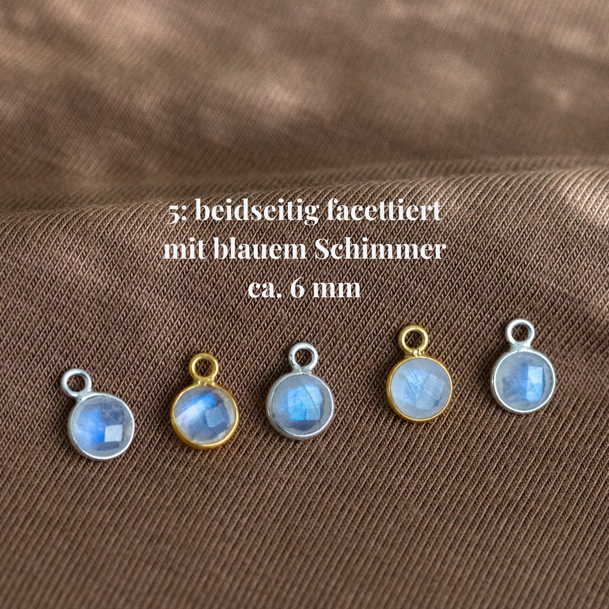 Fünf runde Mondsteine mit goldenem und silbernem Rahmen auf Stoff ausgelegt. Beschriftung mit Hinweisen zu Maßen und Qualität.
