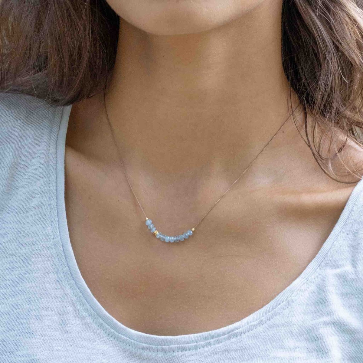 Am Hals des Models hängt eine feine Seidenkette mit kleinen Aquamarin-Rondellen und goldenen Akzenten.