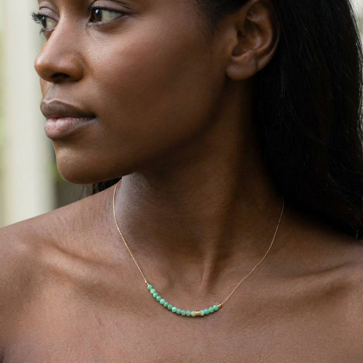 Am Hals des Models hängt eine feine Seidenkette mit einer Reihe grüner Chrysopras-Rondelle und goldenen Akzenten in der Mitte.