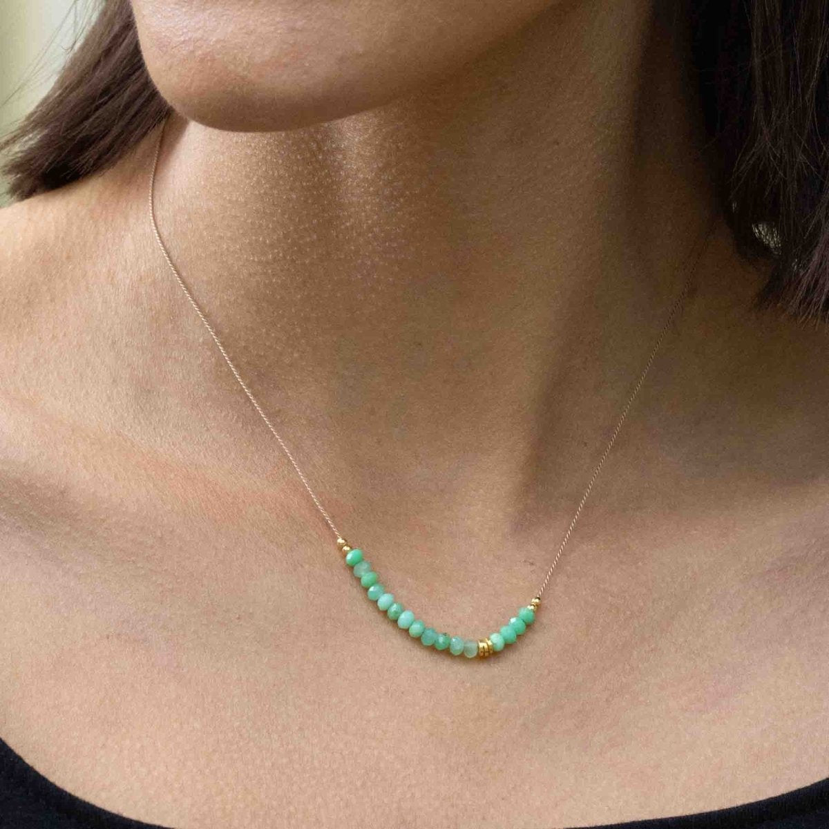 Am Hals des Models hängt eine feine Seidenkette mit einer Reihe grüner Chrysopras-Rondelle und goldenen Akzenten in der Mitte.
