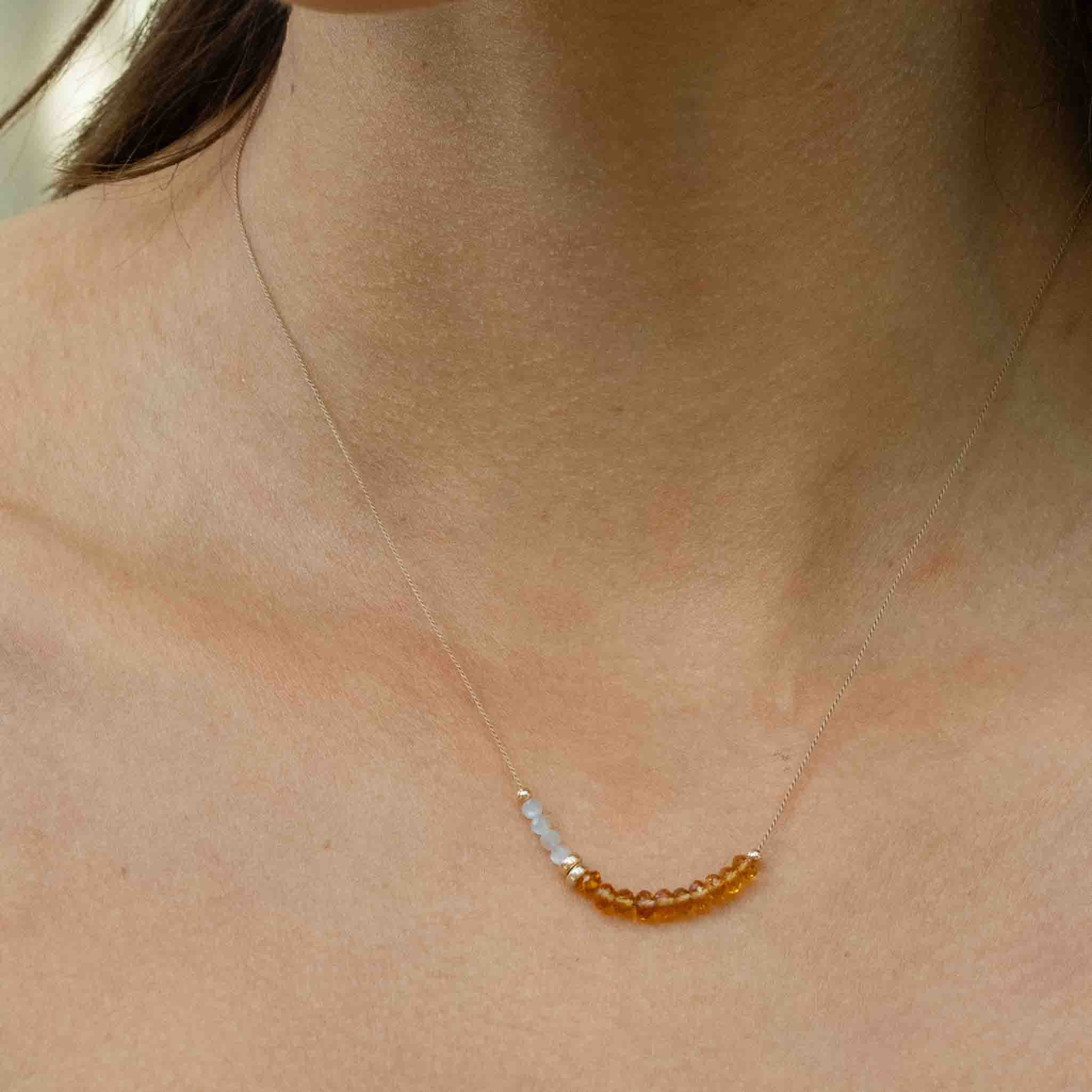 Am Hals des Models hängt eine kurze Halskette mit kleinen Mondsteinen und Citrinen, aufgezogen auf dünne Seide.