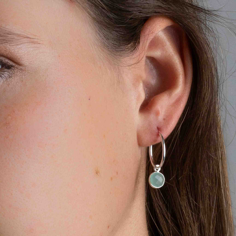 Nahaufnahme einer silbernen Creole mit einem kleinen Aqua Chalcedon am Ohr des Models