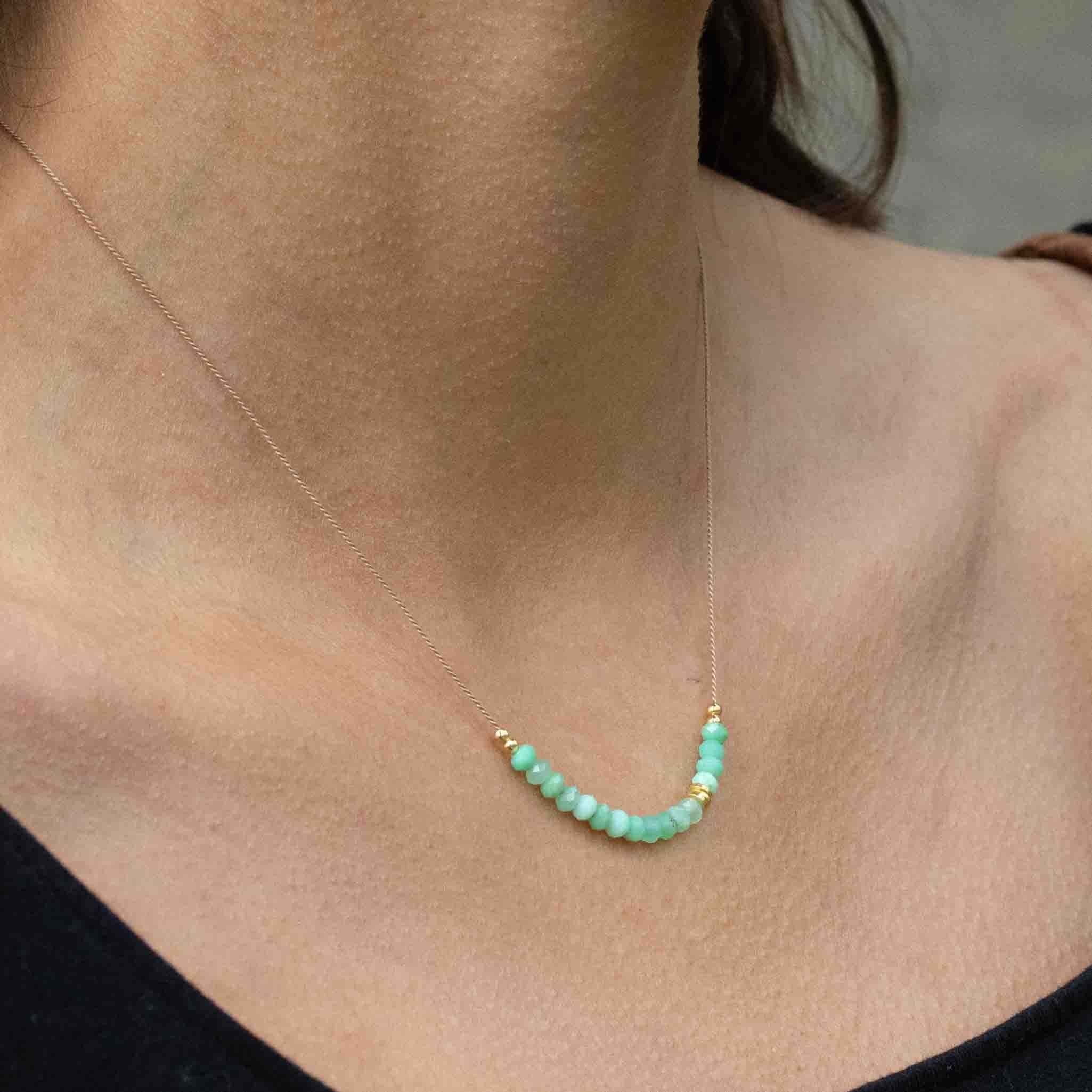 Am Hals des Models hängt eine feine Seidenkette mit einer Reihe grüner Chrysopras-Rondelle und goldenen Akzenten in der Mitte.