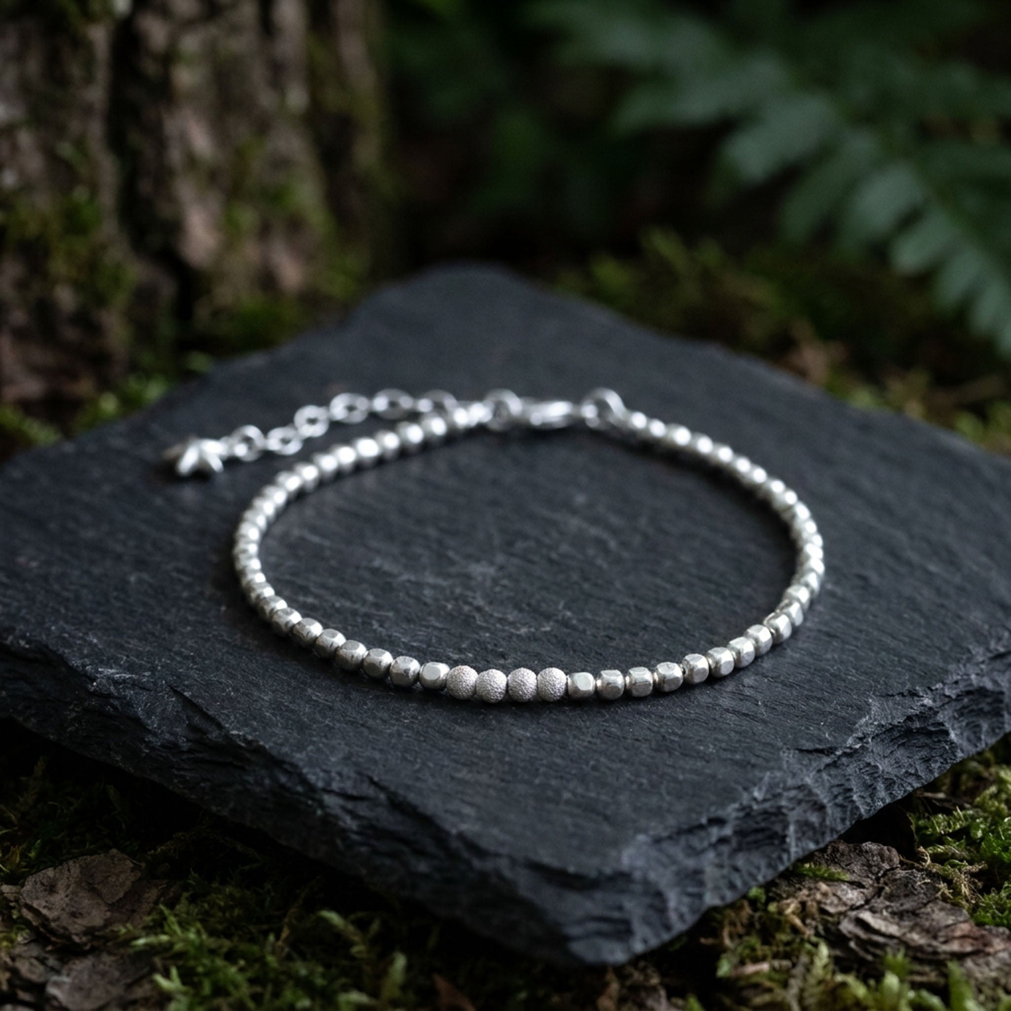 925 Silber Würfel-Armband mit gefrosteten Perlen in der Mitte auf dunkle Steinplatte ausgelegt.