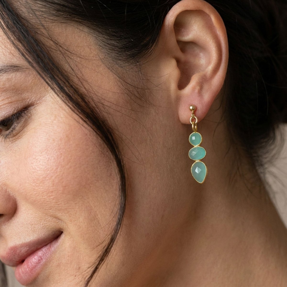 Am Ohr des Models hängt ein goldener Ohrstecker mit drei Aqua Chalcedonen.