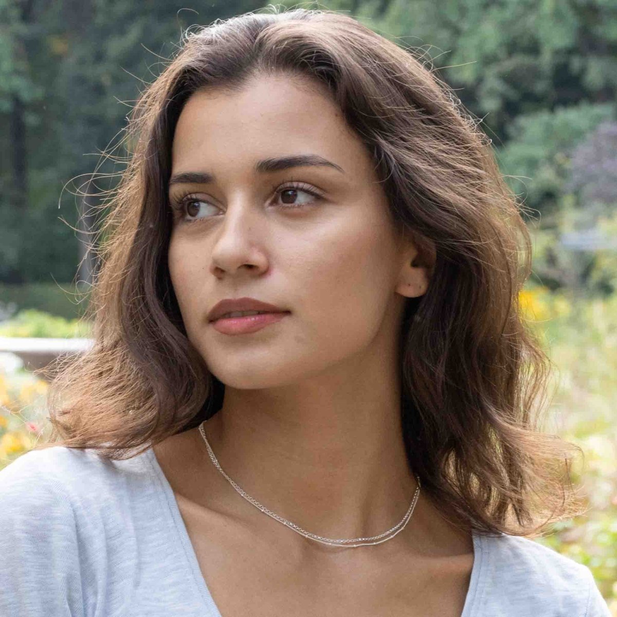 Am Hals des Models hängt eine kurze, doppelreihige Silberkette. 