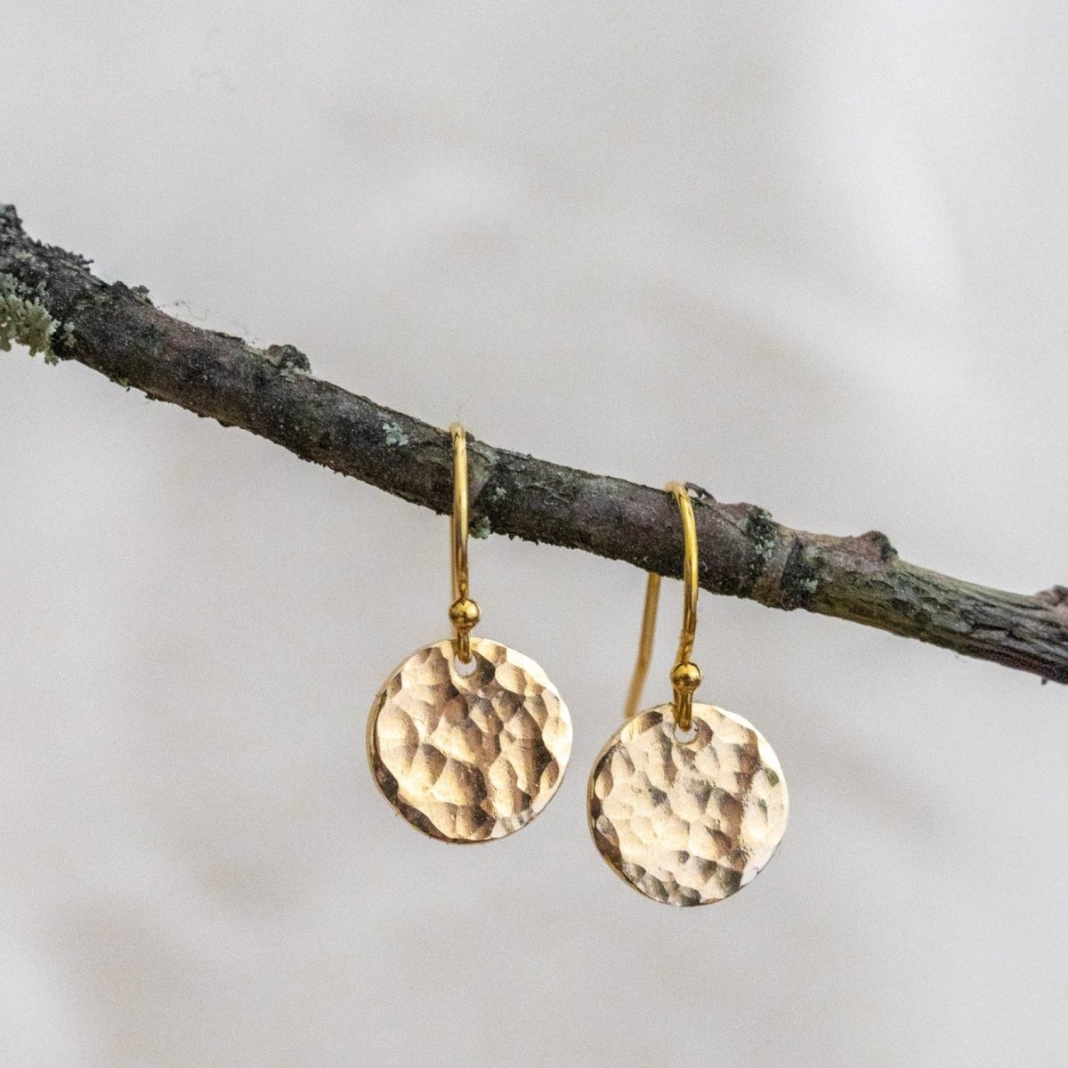 Hängende Gold-Ohrringe mit gehämmerten, runden Plättchen.