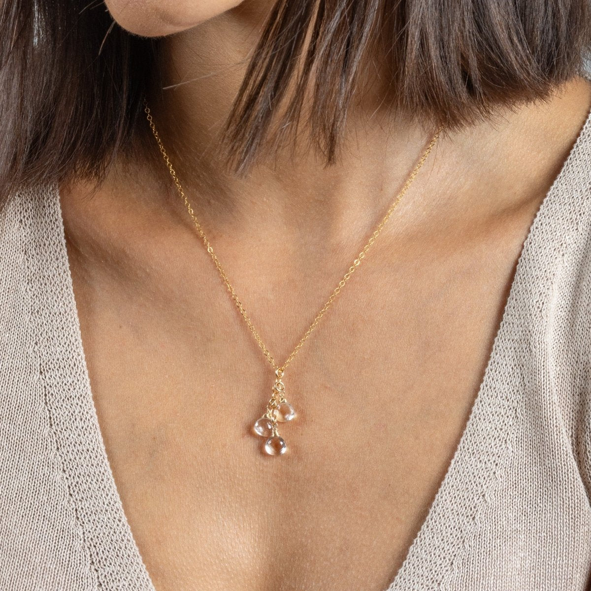 Eine feine Goldkette mit drei untereinander angebrachten, kleinen Bergkristalltropfen hängt am Hals des Modells.