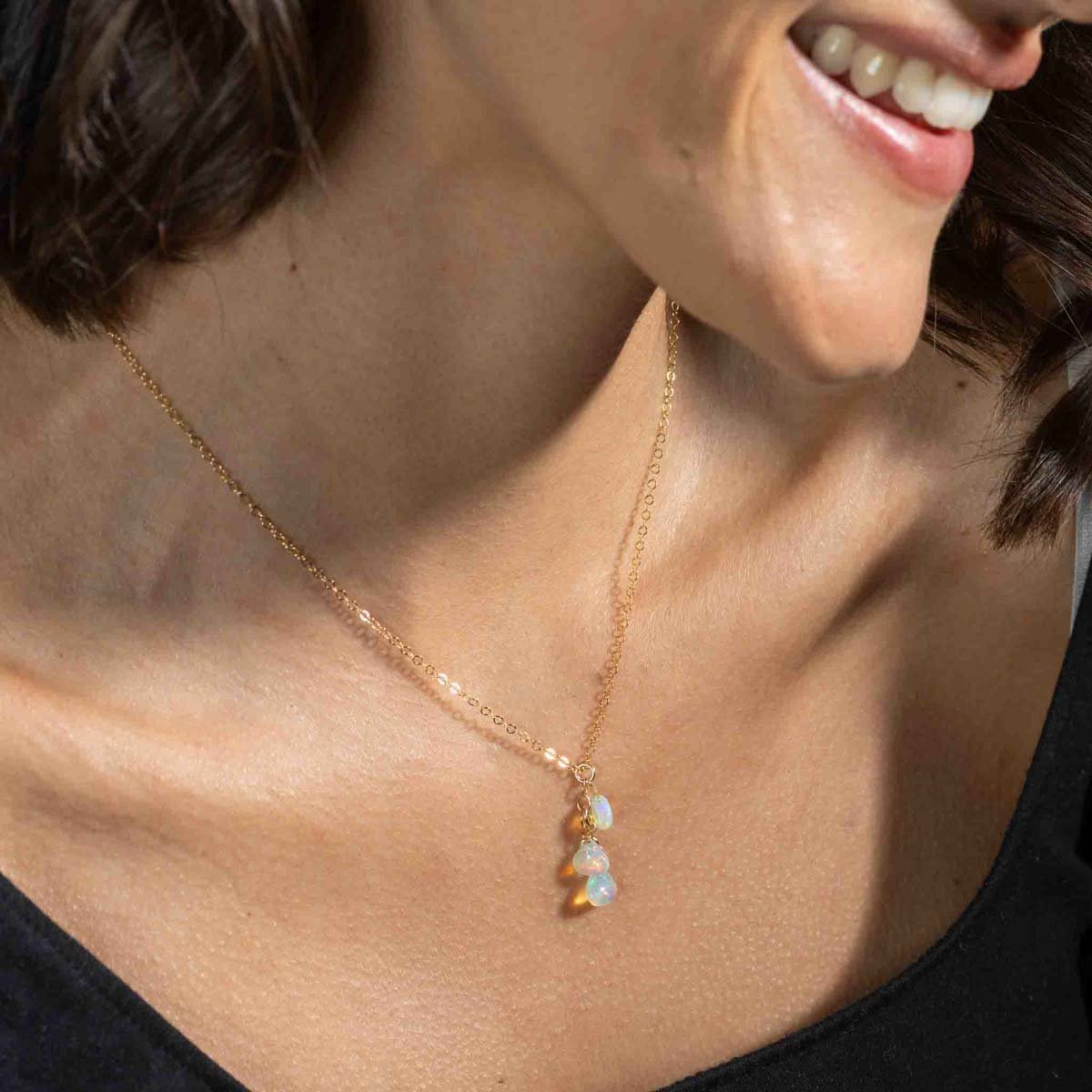 Am Hals des Models hängt eine zarte Goldkette mit drei Opal-Anhängern.
