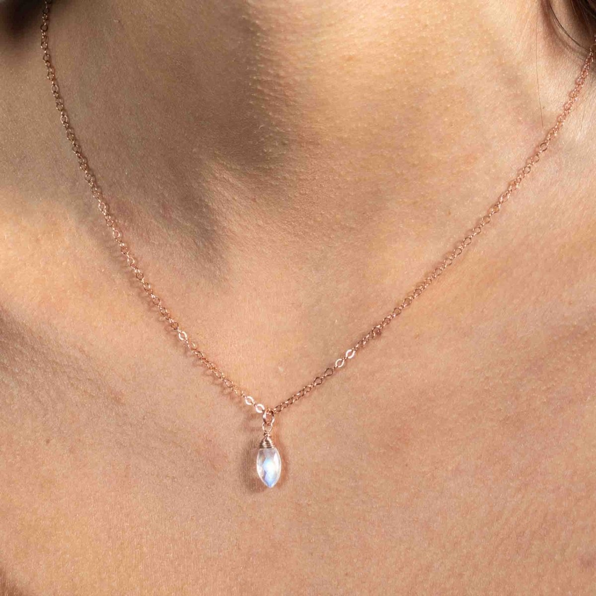 Ein kleiner Mondstein-Anhänger an einer zierlichen Rosé Goldkette hängt am Hals des Models.