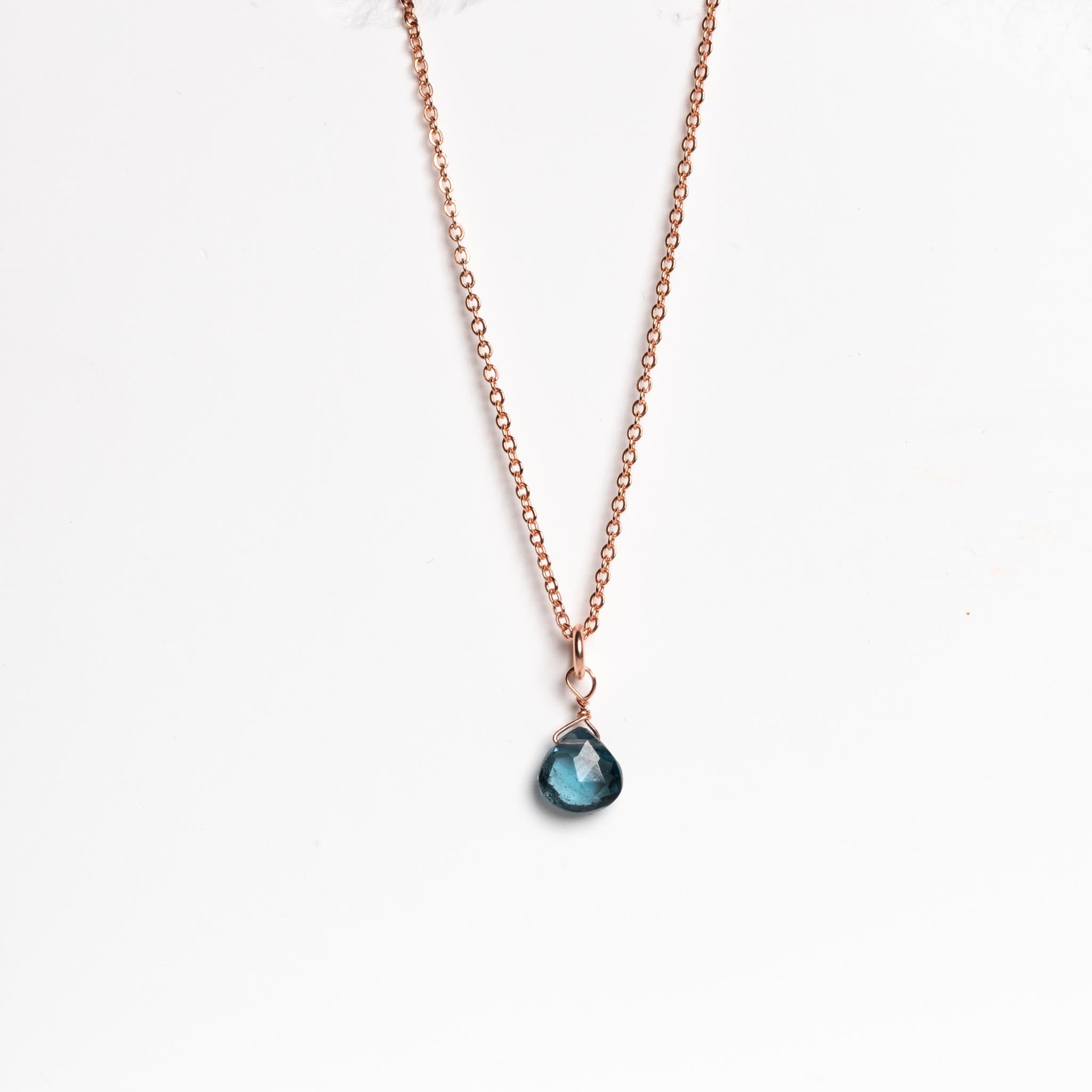 Feine Rosegold Kette mit kleinem London Blautopas-Anhänger vor weißem Hintergrund, handgemacht von Mayam Berlin