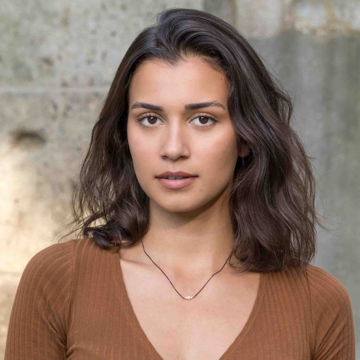 Am Hals des Models hängt eine schwarze Silberkette mit drei weißen Perlen in der Mitte.
