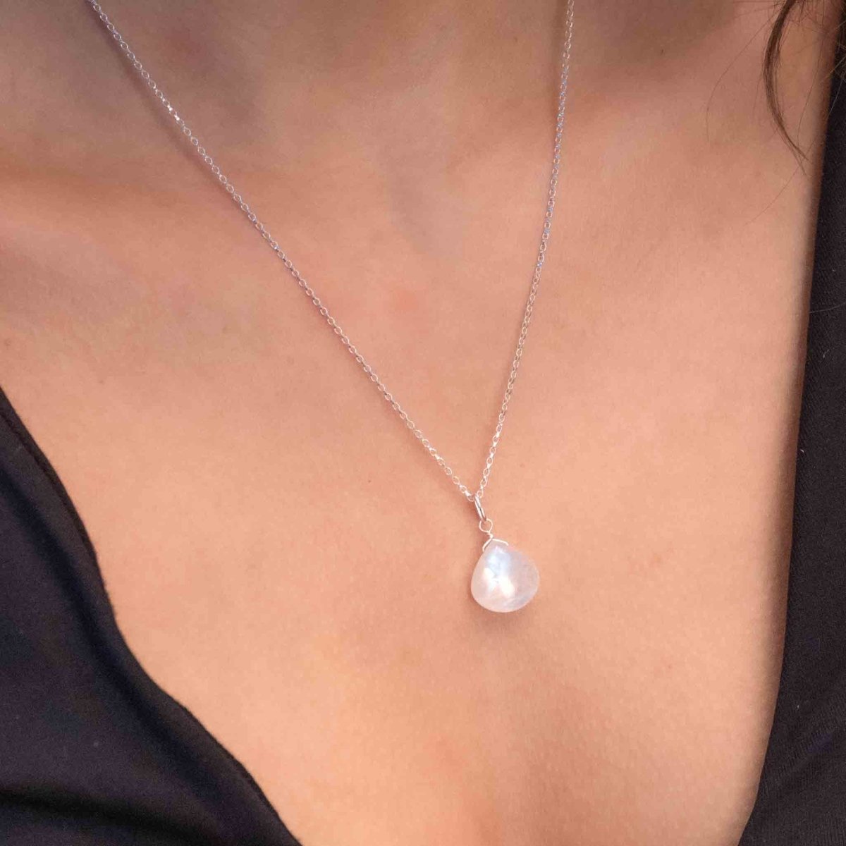 Am Hals des Models hängt eine Silberkette mit einem bläulich schimmernden Mondstein-Anhänger.