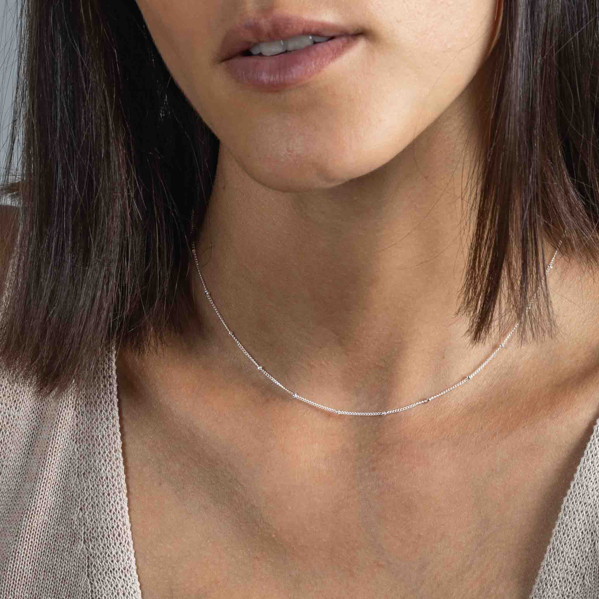 Kurze, silberne Satellitenkette am Hals des Models.
