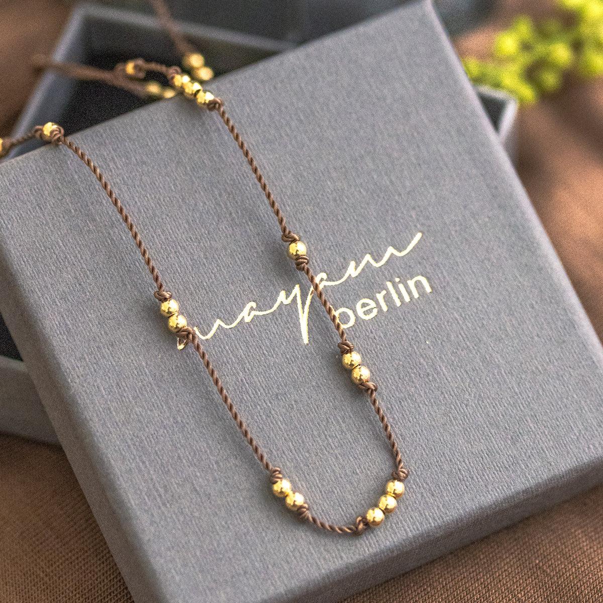 Dünne, beige Kordelkette mit unregelmäßig verteilten Goldperlen ausgelegt auf Mayam Berlin Schmucketui.