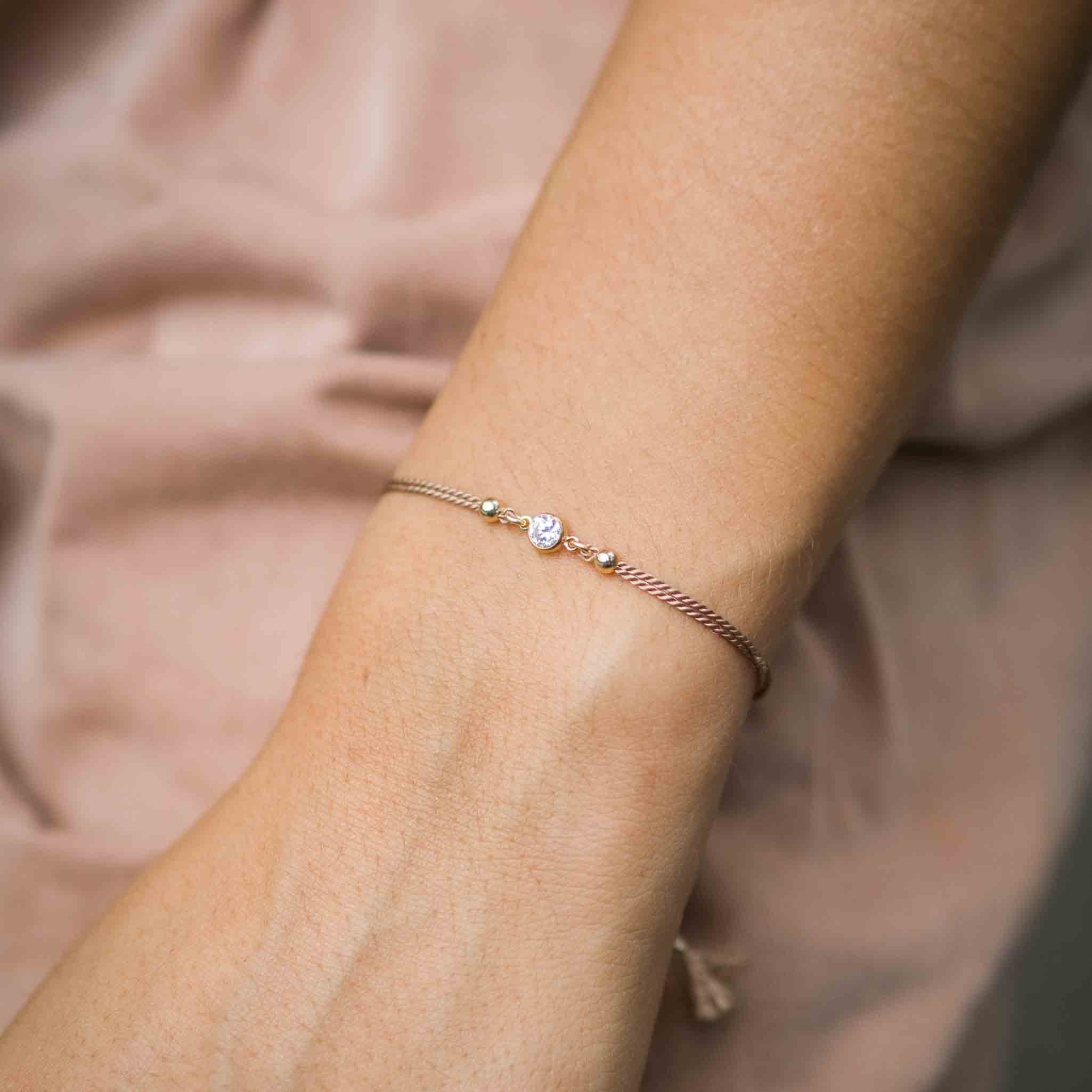 Beiges Seidenarmband mit weißem Zirkonia Stein in der Mitte am Handgelenk des Models | MAYAMBERLIN