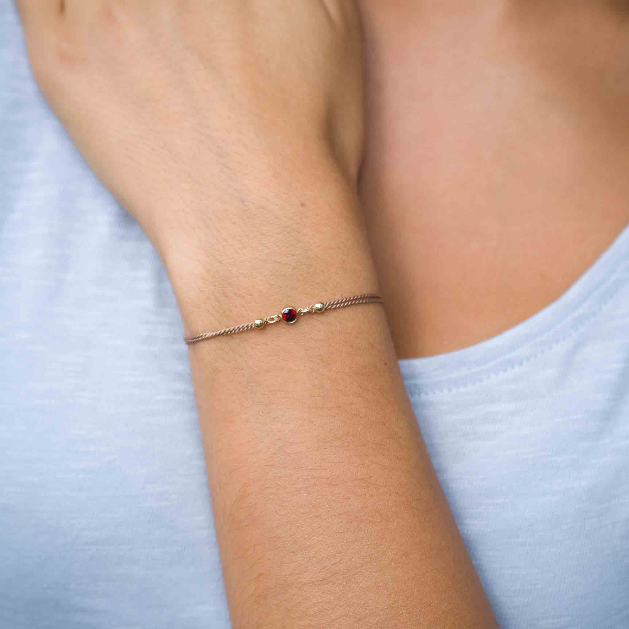 Beiges Seidenarmband mit weinrotem Zirkonia am Handgelenk des Models | MAYAMBERLIN